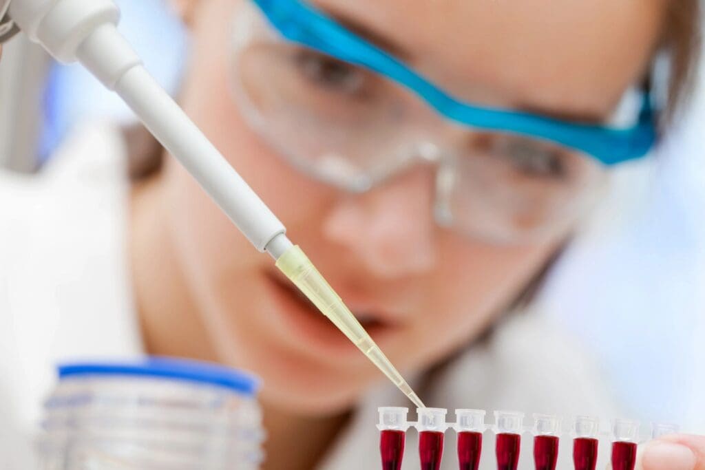 Scientist pipetting blood samples into tubes.